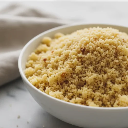 A bowl of Leftover Turkey Noodle Soup sits centered on a marble surface. The soup features golden noodles and chunks of turkey in a clear broth. A linen napkin sits slightly out-of-focus behind the bowl.